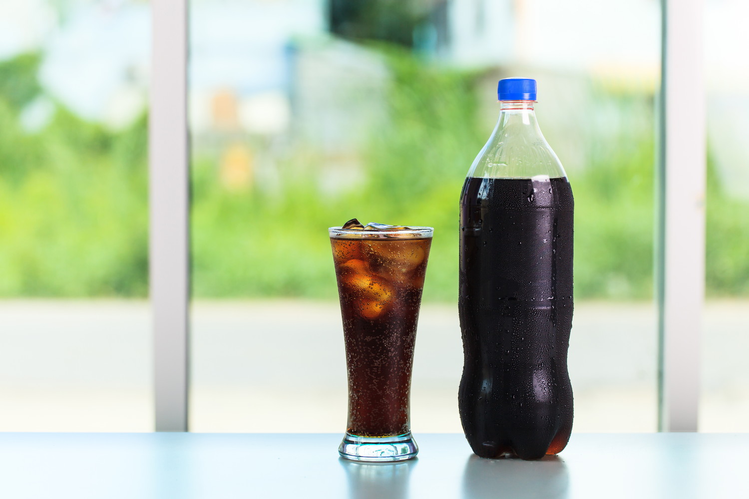 テーブルの上に置かれたコーラのボトルとコップ