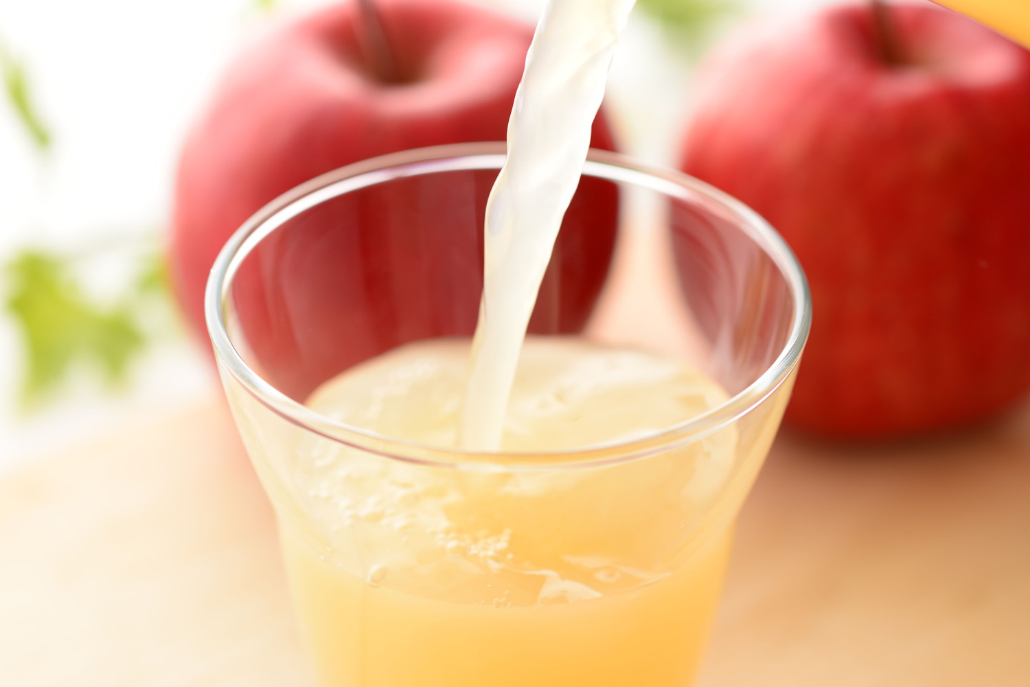 グラスにりんごジュースが注がれている光景